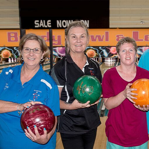 Two female support workers with support recipient playing ten pin bowling