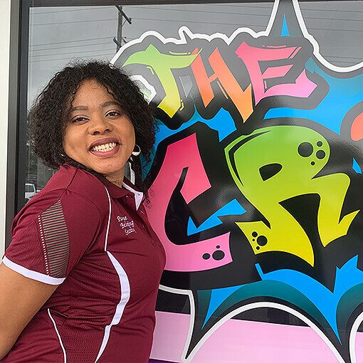 Happy SCSS NDIS care provider in front of graffiti signage