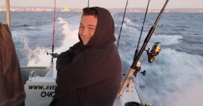 SCSS client Jake Brown smiling at camera on boat with fishing rods in the background