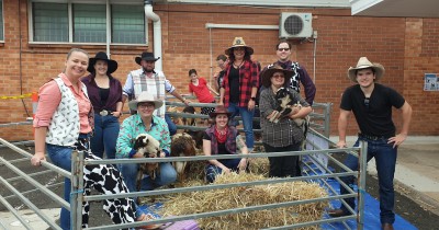 Group of Clients and Staff celebrating Disabilty Action Week on hay bales