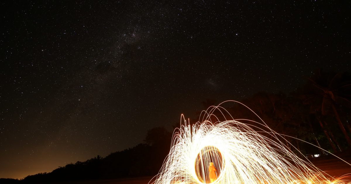 Person standing on a beach at night time with light circles around them
